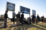 The secretary of war alongside Space Force and Army leadership unveil signs in a field.