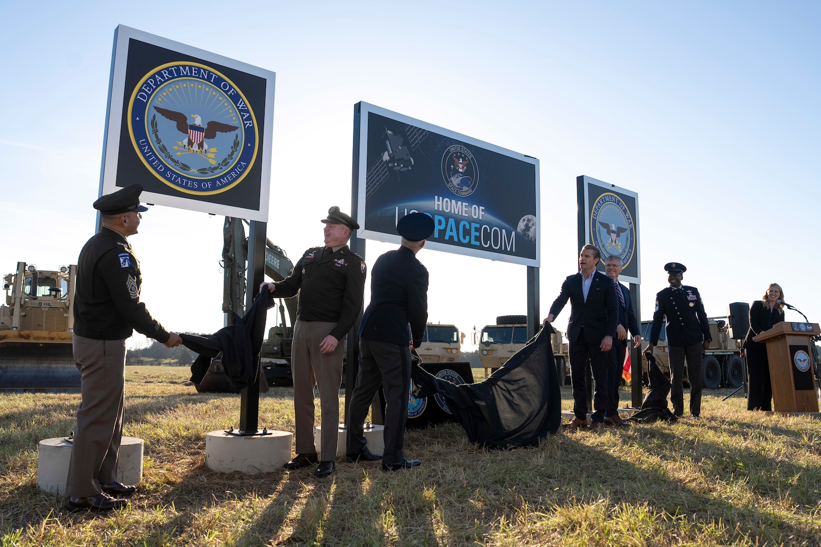 The secretary of war alongside Space Force and Army leadership unveil signs in a field.