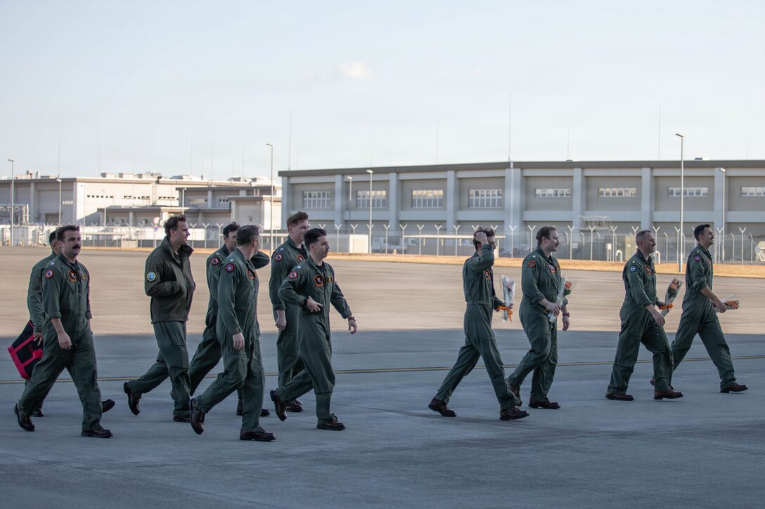U.S. Navy pilots with Strike Fighter Squadron (VFA) 147, Carrier Air Wing (CVW) 5, prepare to greet friends and family members at Marine Corps Air Station Iwakuni, Japan, Dec. 6, 2025.  CVW-5 aircraft and personnel return from being forward-deployed on the Nimitz-class aircraft carrier USS George Washington (CVN-73) which provided air superiority and all-weather offensive air-to-surface attack capabilities, to maintain a free and open Indo-Pacific. (U.S. Marine Corps photos by Lance Cpl. Tyler Bassett)