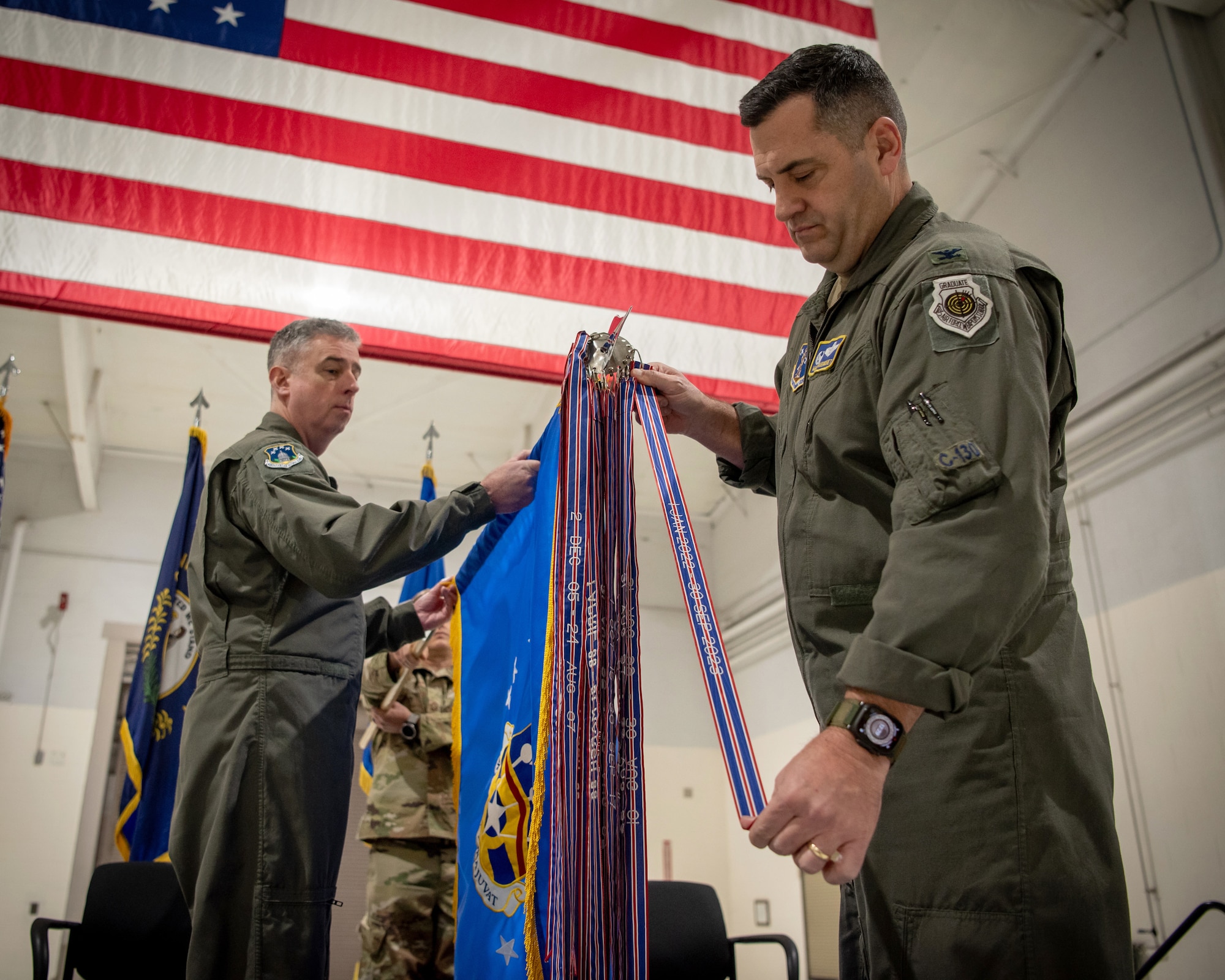 Col. Matthew Quenichet, commander of the 123rd Airlift Wing, pins the unit’s 21st Air and Space Outstanding Unit Award streamer to the wing guidon during a ceremony at the Kentucky Air National Guard Base in Louisville, Ky., Dec. 14, 2025. The new honor, previously known as the Air Force Outstanding Unit Award, continues the unit’s legacy as the most decorated tactical airlift wing in the United States Air Force. (U.S. Air National Guard photo by Master Sgt. Joshua Horton)