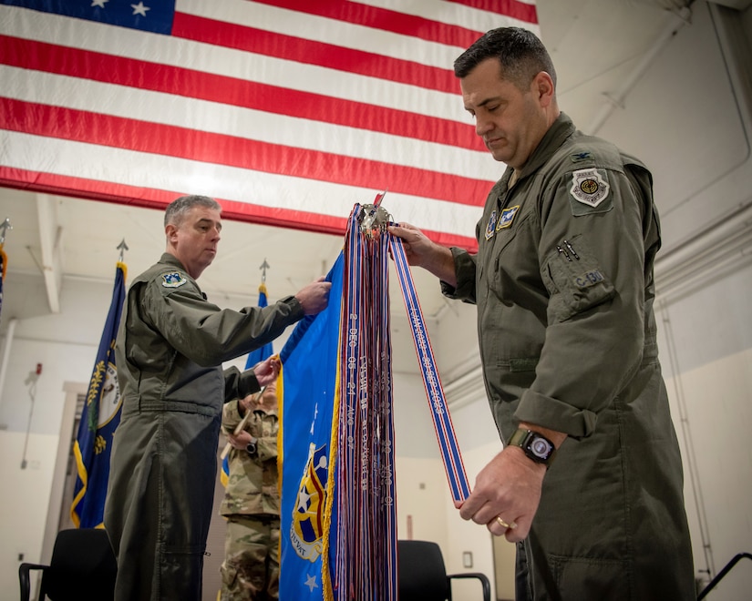 Col. Matthew Quenichet, commander of the 123rd Airlift Wing, pins the unit’s 21st Air and Space Outstanding Unit Award streamer to the wing guidon during a ceremony at the Kentucky Air National Guard Base in Louisville, Ky., Dec. 14, 2025. The new honor, previously known as the Air Force Outstanding Unit Award, continues the unit’s legacy as the most decorated tactical airlift wing in the United States Air Force. (U.S. Air National Guard photo by Master Sgt. Joshua Horton)