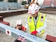 U.S. Army Corps of Engineers – Japan Engineer District (USACE JED) Yokota Resident Office team members, Rion Ogawa, an engineering technician (left), and Tatsuya Kokubu, a construction representative, sign a structural beam during a Topping Off ceremony on October 3rd, 2025. The structural beam was the last to be placed in the Yokota Air Base’s currently undergoing construction Corrosion Control Hangar. During the ceremony, special thanks were provided to the intercultural team members involved in the project, and how projects designed and constructed by JED often bring together individuals from a wide range of professional and international backgrounds. Courtesy photo provided by Gilbane Japan.