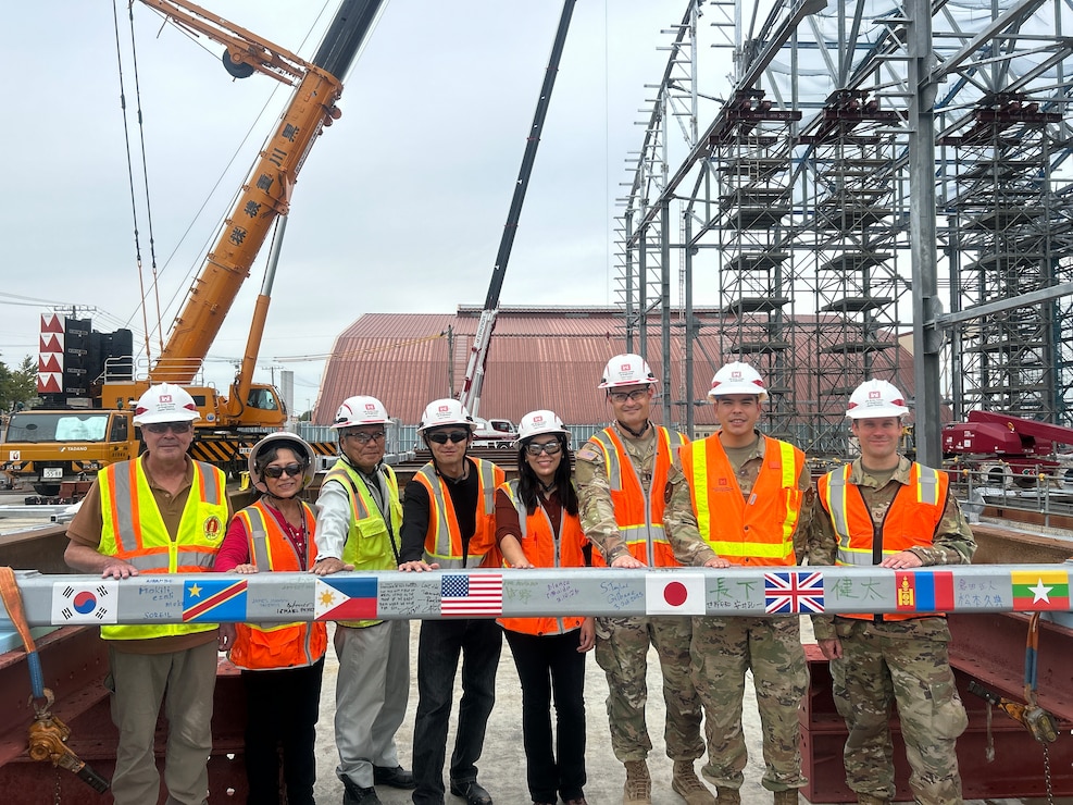 Members from the U.S. Army Corps of Engineers – Japan Engineer District (USACE JED) Yokota Resident Office, pose for a photo with the last structural beam to be installed in the currently-under construction Corrosion Control Hangar, during a Topping Out ceremony, October 3rd, 2025. A topping-out ceremony is a long-standing construction tradition signifying that the final structural beam has been placed atop a building’s frame. The milestone symbolizes progress, safety, and teamwork among the project’s engineers, contractors, and partners as construction moves from heavy structural work into interior and systems installation. Courtesy photo provided by Gilbane Japan.