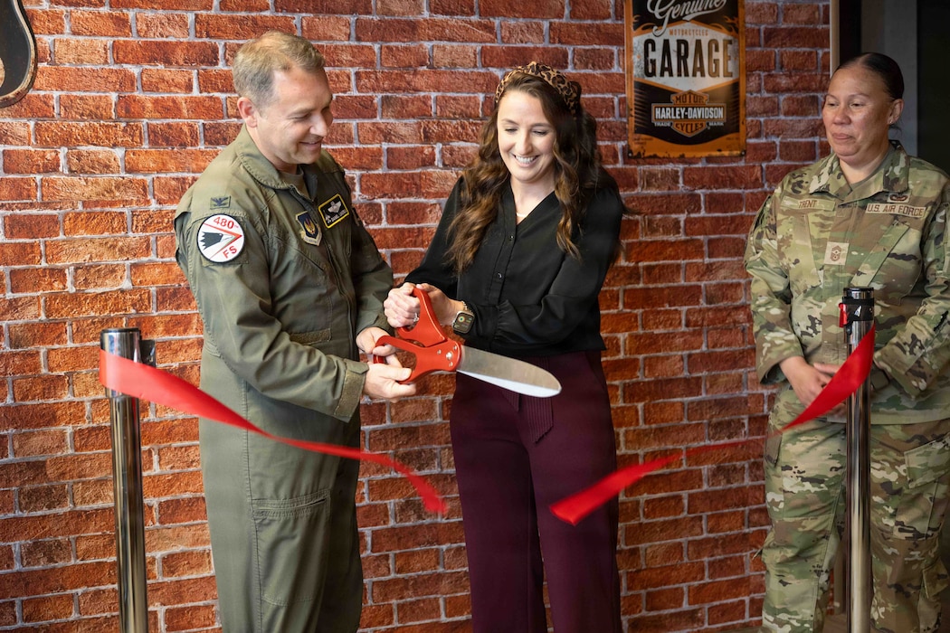 U.S. Air Force Col. Daniel Lindsay, left, 52nd Fighter Wing Deputy Commander, and Katherine Kumar, 52nd Mission Support Group key support liaison, cut the ribbon to commemorate the opening of the Brick House at Spangdahlem Air Base, Germany, Sept. 30, 2025. The Brick House demonstrates a commitment to building morale and strengthening resilience among Airmen. (U.S. Air Force photo by Senior Airman Darius Frazier)
