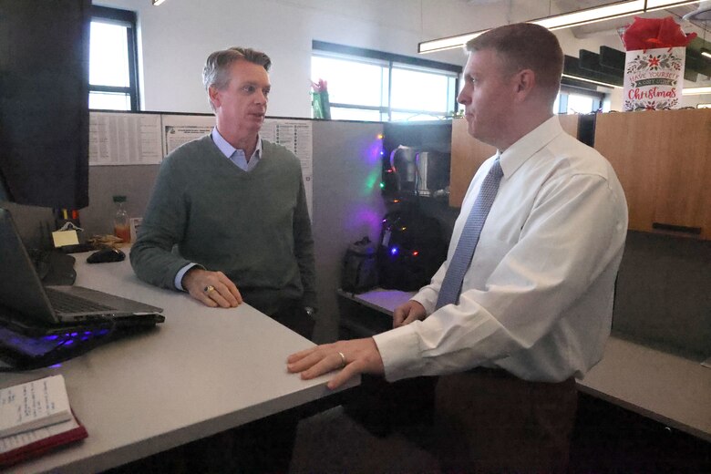 Two men talking at a desk.