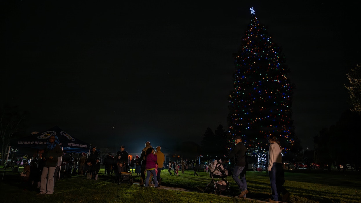 A wide shot of Airmen and family members gathering around a Christmas Tree