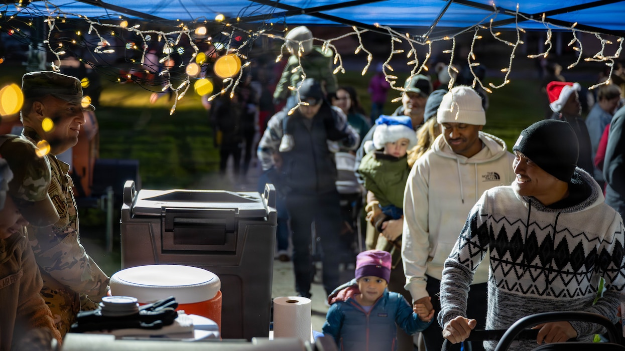 Families walk through a line to get hot cocoa from service members