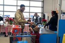 A U.S. Air Force Defender assigned to Minot Air Force Base helps a child check out holiday gifts during the annual Cops and Kids event at a Walmart in Minot, North Dakota, Dec. 14, 2025. The event paired children with law enforcement officers and military personnel to shop for gifts, thereby strengthening community connections. (U.S. Air Force photo by Senior Airman Luis Gomez)