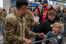 A U.S. Air Force Defender assigned to 791st Missile Security Forces Squadron gives a fist bump to a child during the Cops and Kids event at Walmart in Minot, North Dakota, Dec. 14, 2025. The event paired children with law enforcement officers and military personnel to shop for gifts, thereby strengthening community connections. (U.S. Air Force photo by Senior Airman Luis Gomez)