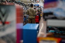 A U.S. Air Force Defender assigned to Minot Air Force Base shops with a child during the Cops and Kids event at Walmart in Minot, North Dakota, Dec. 14, 2025. The event brought together military members and families to support local youth and strengthen community partnerships during the holiday season. (U.S. Air Force photo by Senior Airman Luis Gomez)