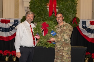 Doug Poore, (right), Kent County coordinator for Wreaths Across America, presents U.S. Air Force Col. Jamil Musa, 436th Airlift Wing commander with a holiday wreath during a Wreaths Across America event in Dover, Delaware, Dec. 11, 2025. Each December, volunteers travel from Maine to Arlington National Cemetery to place holiday wreaths on the graves of thousands of American veterans. (U.S. Air Force photo by Mauricio Campino)