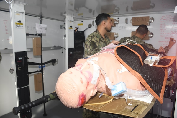 A medical simulation mannequin patient receives care inside on of two Rapid Emergency Medical (REM) Pod/Units during a  mass casualty response drill on Naval Air Station North Island.  Members of the Military Sealift Command (MSC) hospital ship USNS Mercy (T-AH 19) Medical Treatment Facility (MTF) along with Marines from the Expeditionary Medical Facility, 4th Marine Medical Battalion and the Marine Corps Warfighting Lab participated in the drill as part of the larger, multi-service exercise, Steel Knight 2025, held at Marine Base Camp Pendleton, and tested the MTF’s ability to triage, treat and transport multiple simulated patients during a crisis.