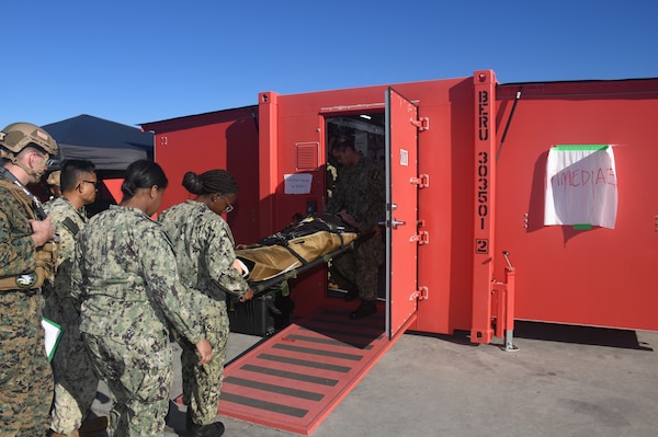 A patient is moved into one of the two Rapid Emergency Medical (REM) Pod/Units for continued treatment.  Members of the Military Sealift Command (MSC) hospital ship USNS Mercy (T-AH 19) Medical Treatment Facility (MTF) along with Marines from the Expeditionary Medical Facility, 4th Marine Medical Battalion and the Marine Corps Warfighting Lab participated in the drill as part of the larger, multi-service exercise, Steel Knight 2025, held at Marine Base Camp Pendleton, and tested the MTF’s ability to triage, treat and transport multiple simulated patients during a crisis.