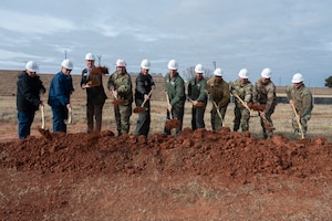 many men stand on dirt with gold shovels