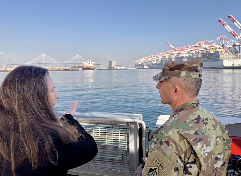 With ships and cranes looming in the background, Brig. Gen. John Lloyd, U.S. Army Corps of Engineers South Pacific Division commander, right, speaks with Suzanne Plezia, managing director of the Port of Long Beach, left, during a boat tour of the port Dec. 2 in Long Beach, California.