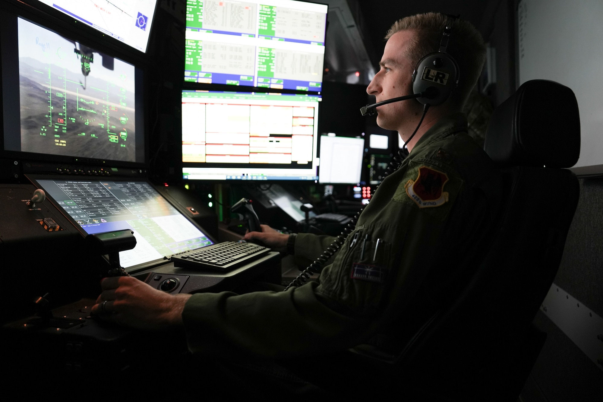 A man in a flight suit operates a joystick.