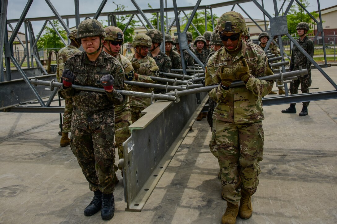 U.S. Soldiers assigned to 11th  Engineer Battalion, 2nd Infantry Division Sustainment Brigade, 2nd Infantry Division/ROK-U.S. Combined Division, and ROK army soldiers assigned to 1117th Engineer Group, 2nd Operation Command, lifts a metal support beam on Camp Humphreys, South Korea, June 10, 2024.