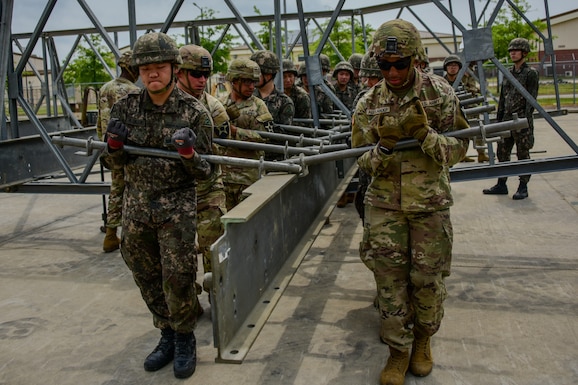 U.S. Soldiers assigned to 11th  Engineer Battalion, 2nd Infantry Division Sustainment Brigade, 2nd Infantry Division/ROK-U.S. Combined Division, and ROK army soldiers assigned to 1117th Engineer Group, 2nd Operation Command, lifts a metal support beam on Camp Humphreys, South Korea, June 10, 2024.