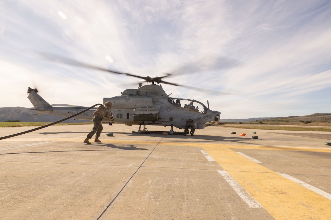 U.S. Marine Corps Lance Cpl. Kelby Dallas, an expeditionary fuels technician with Marine Wing Support Squadron 372, Marine Air Control Group 38, 3rd Marine Aircraft Wing, carries a fuel hose to an AH-1Z Viper assigned to Marine Light Attack Helicopter Squadron (HMLA) 267, Marine Aircraft Group-39, 3rd MAW, at a forward arming and refueling point during exercise Steel Knight 25 at a helicopter outlying landing field, Marine Corps Base Camp Pendleton, California, Dec. 12, 2025. FARP operations support 3rd MAW distributed aviation operations by enabling rotary and tiltrotor aircraft to refuel in forward operating environments, such as the helicopter outlying field, extending operational reach and mission duration across the battlespace. Steel Knight is an annual exercise that strengthens the Navy-Marine Corps team's ability to respond forward, integrate across domains, and sustain Marine Air-Ground Task Force readiness.​(U.S. Marine Corps photo by Cpl. Renee Gray)