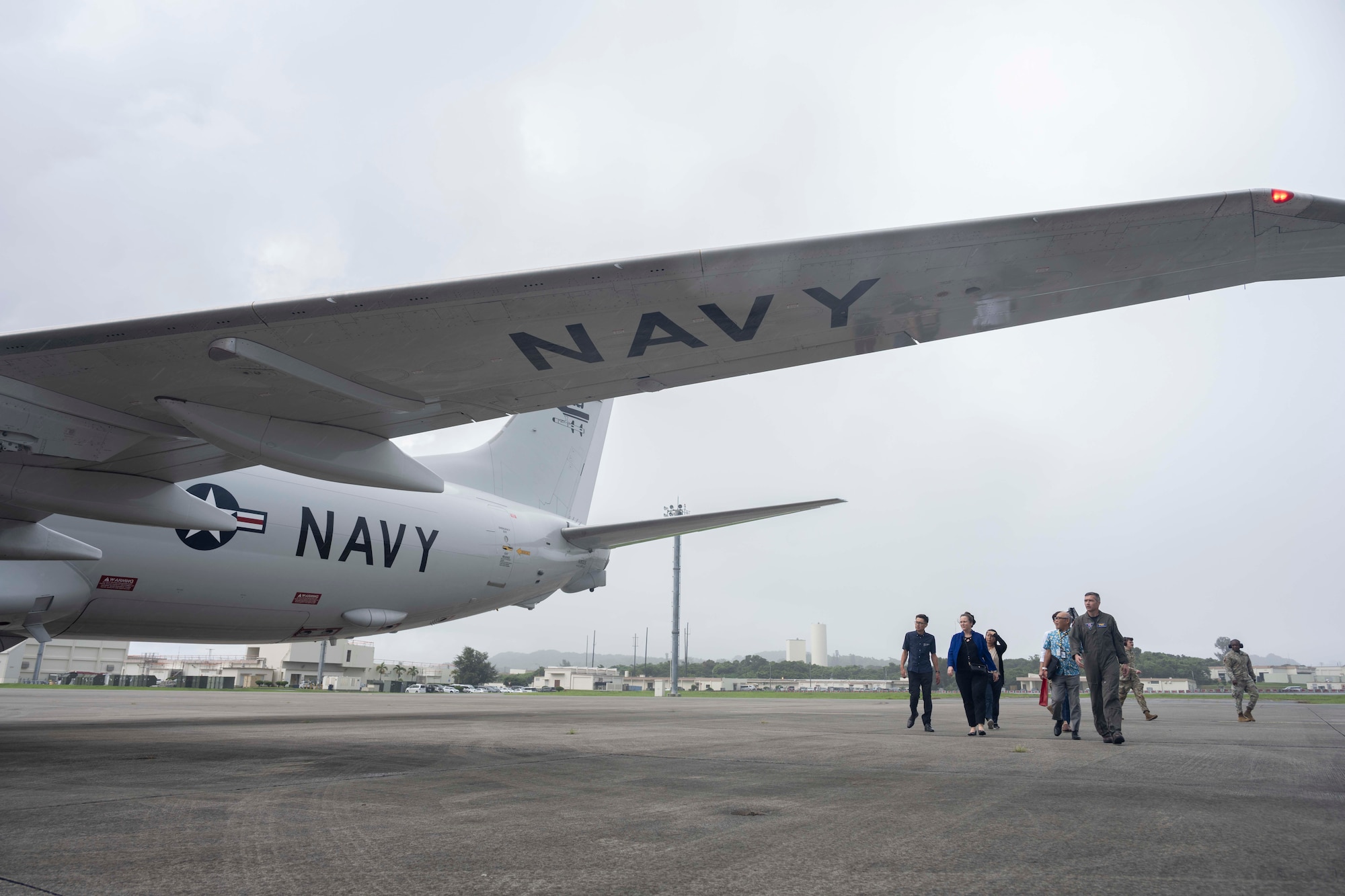 Vistors from the Okinawa Defense Bureau observe a P-8 Poseidon, attached to the "Golden Eagles" of Patrol Squadron (VP) 9, during a brief by Capt. Joseph Parsons, Commander, Fleet Activities Okinawa (CFAO), while touring U.S. Navy assets on Kadena Air Base, Aug. 4, 2025.