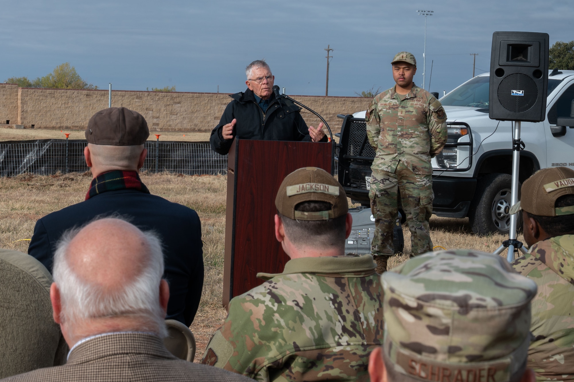 Airmen speak outside while standing behind a lectern