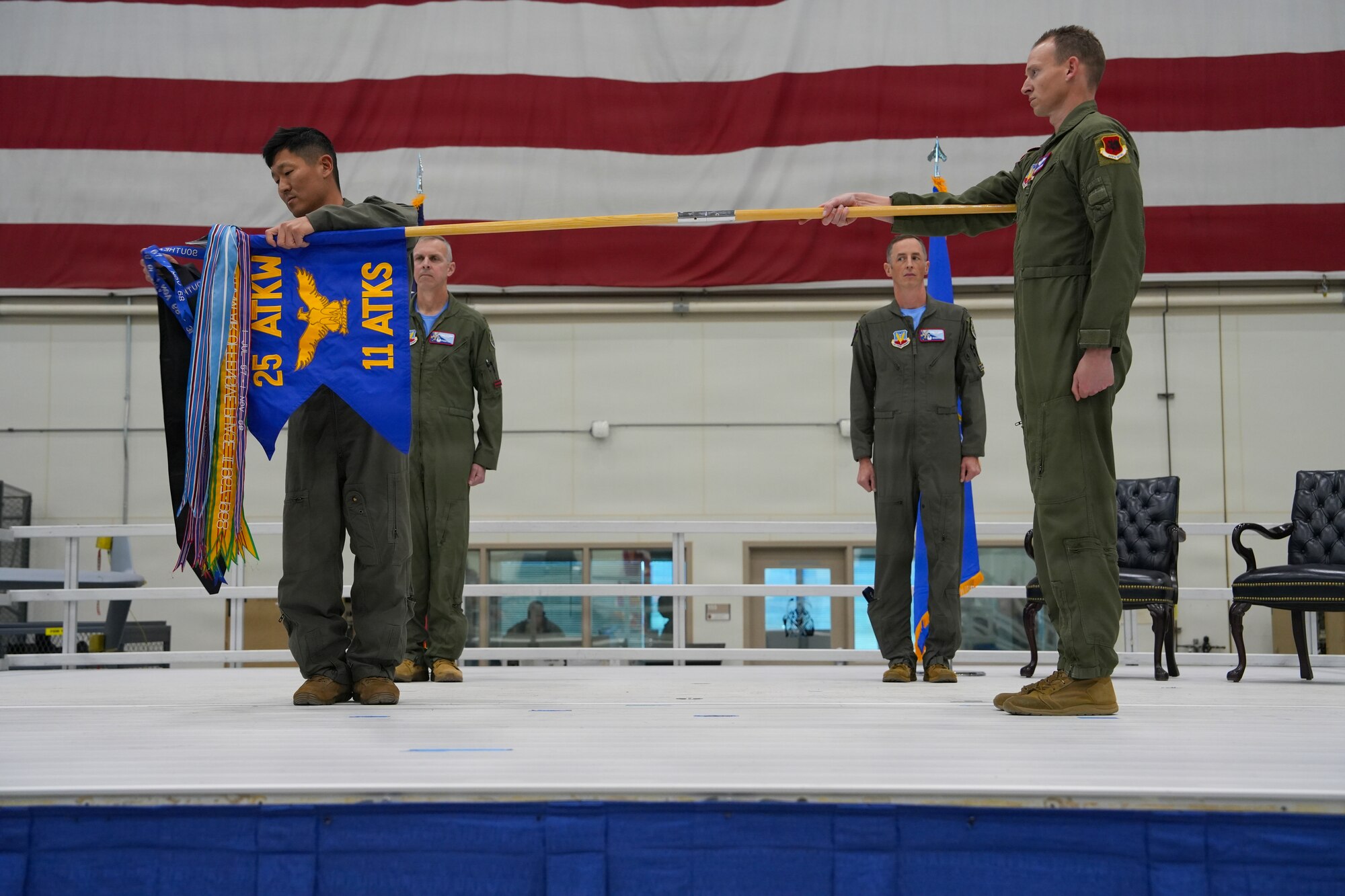 A man in a military uniform places a streamer on a flag