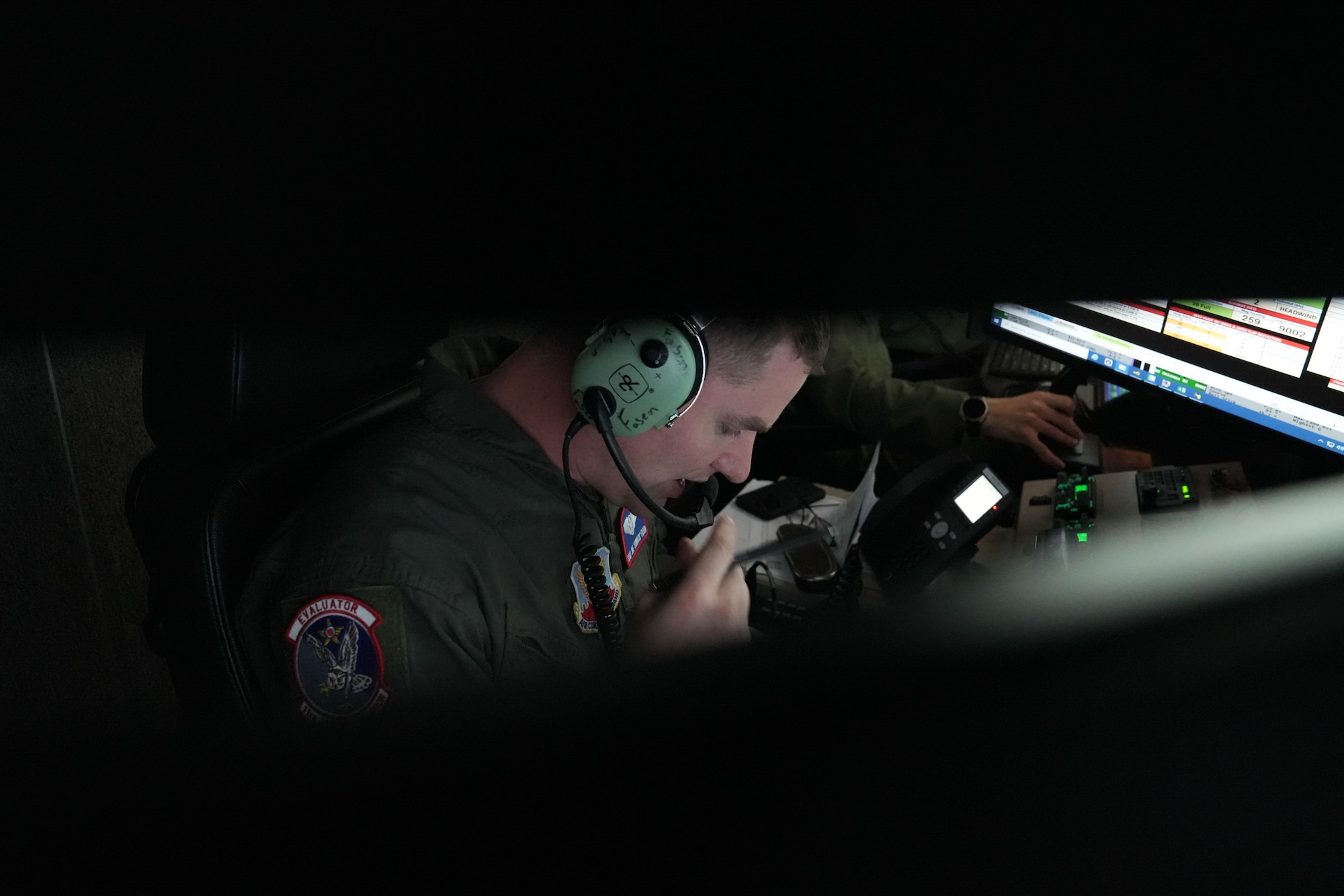 A man in a military uniform wearing headphones speaks into a speaker.