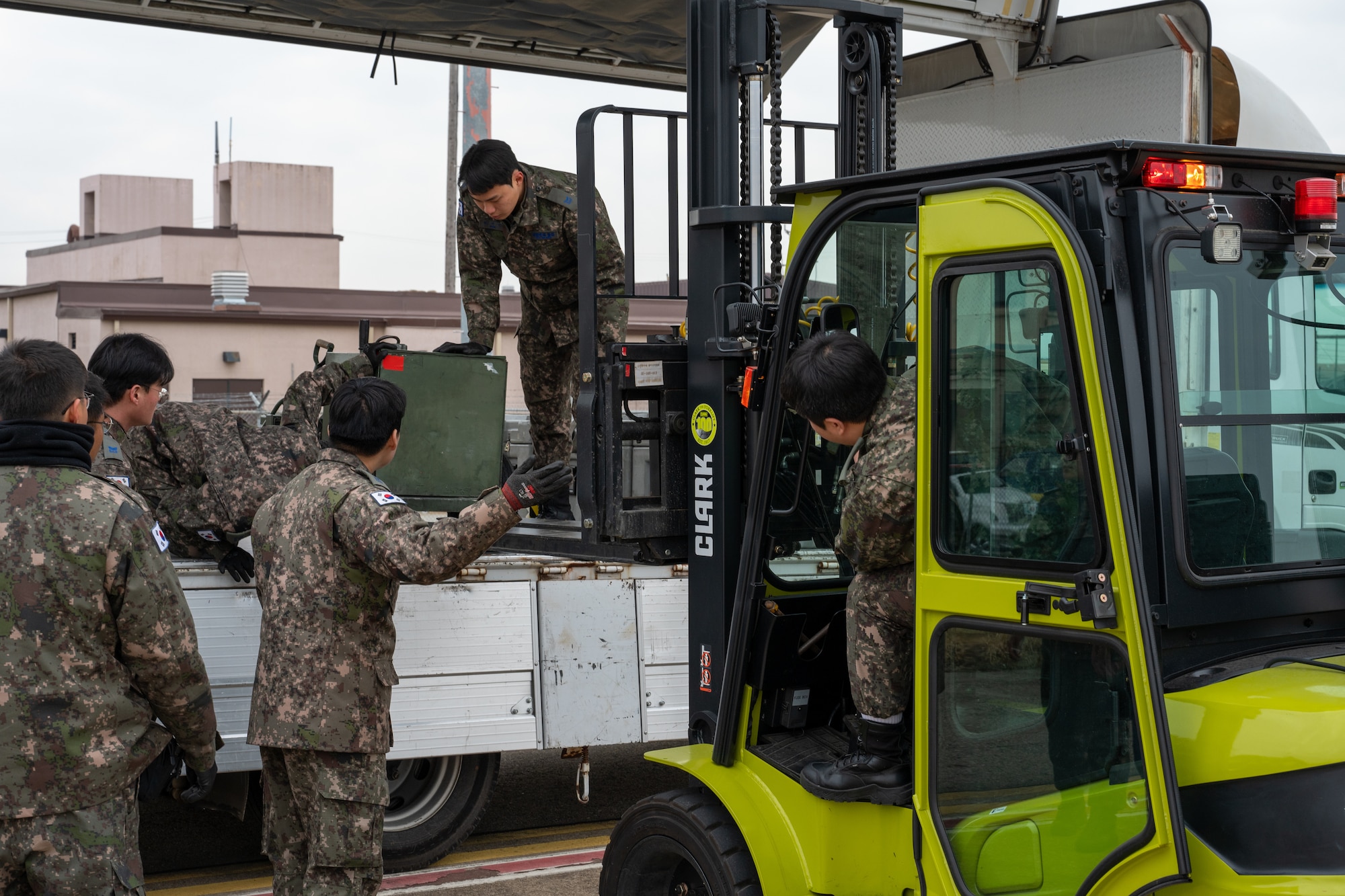 Republic of Korea Air Force Airmen unload equipment from a cargo truck.
