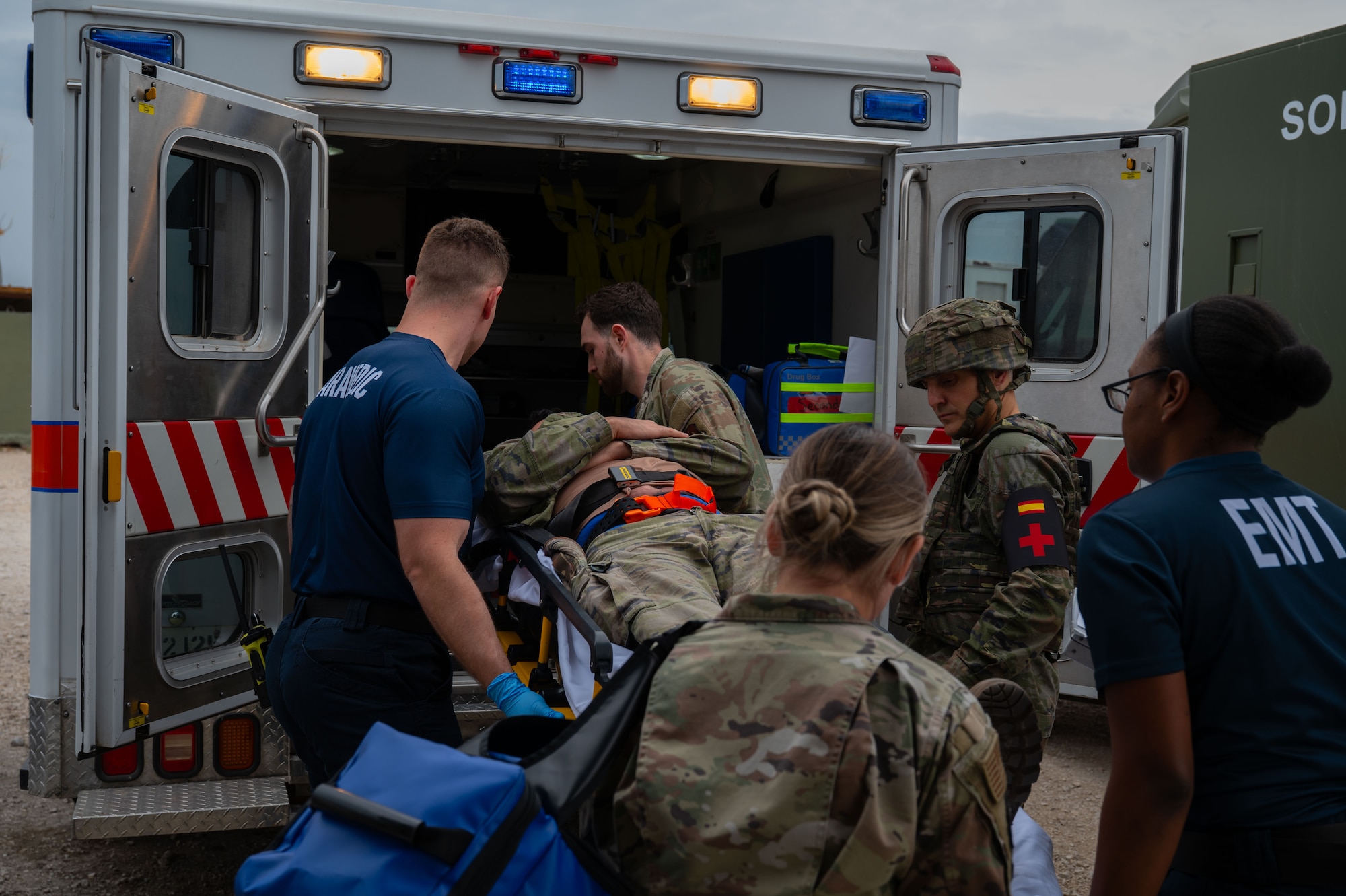 Members of the US. Air Force and Spanish Army members transport simulated victim to ambulance.