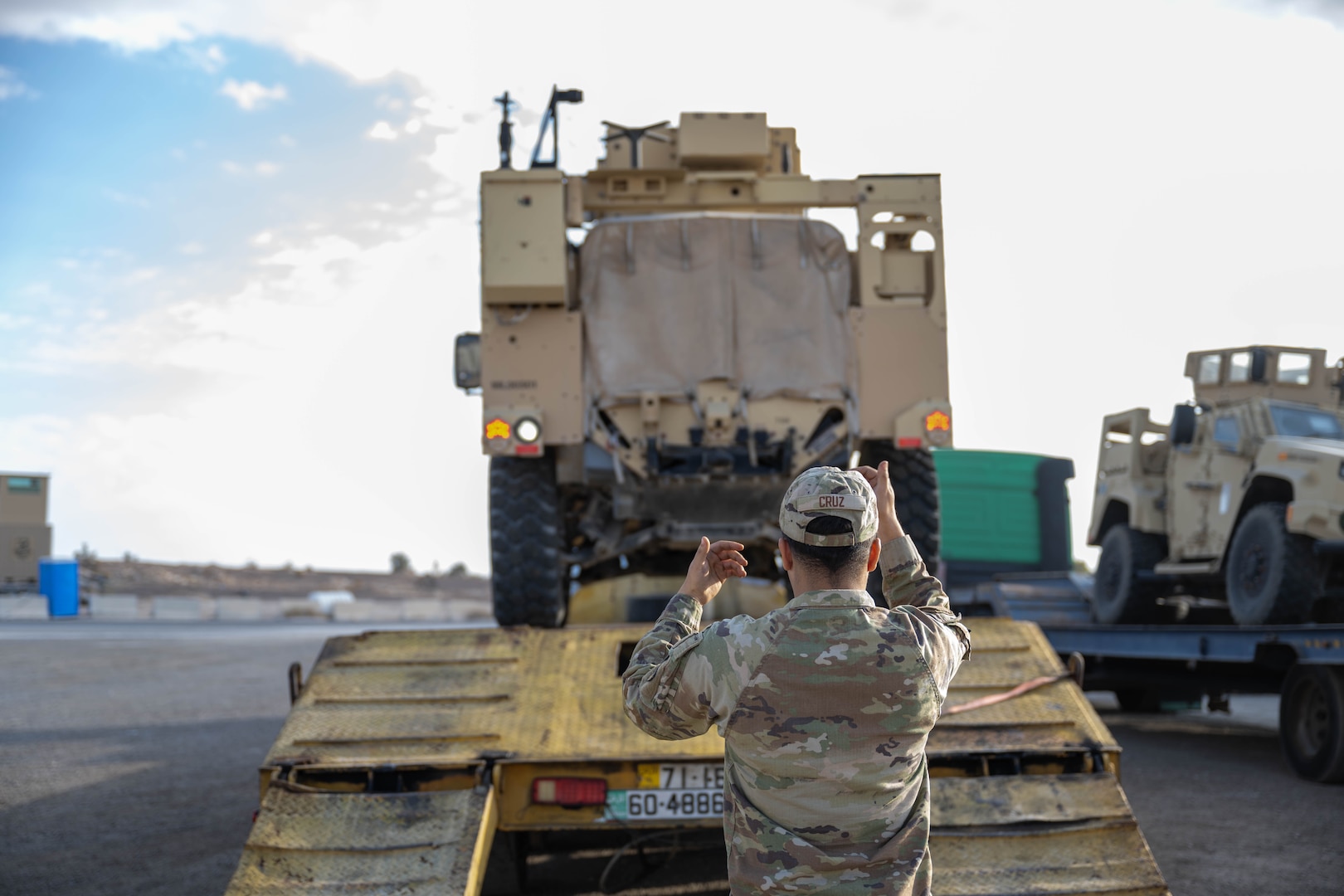 U.S. Air Force Airman 1st Class Daniel Cruz, 332nd Expeditionary Logistics Readiness Squadron vehicle maintainer, guides the operator in a Joint Light Tactical Vehicle off a delivery truck in the U.S. Central Command area of responsibility, Dec. 2, 2025. The JLTV is equipped with structural upgrades, including a new drive shaft and self inflating tires, to better perform in a variety of situations. (U.S. Air Force photo by Senior Airman Kari Degraffenreed)