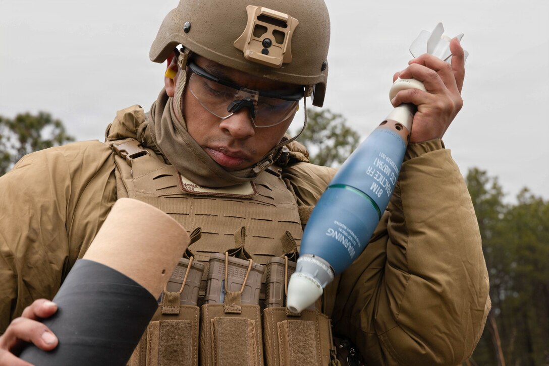 U.S. Marine Corps Pfc. Carlos Escalonagomez, a mortarman, removes an 81mm practice round from its packaging at Joint Base McGuire-Dix-Lakehurst, New Jersey, Dec. 6, 2025. Escalonagomez, with 2nd Battalion, 25th Marine Regiment, 4th Marine Division, maintains readiness through drills and training that develop leadership and technical skills. (U.S. Marine Corps photo by Lance Cpl. Breysson Villacortacampos)