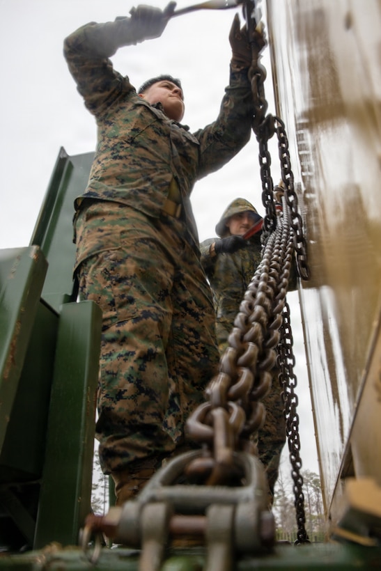 U.S. Marine Corps Lance Cpl. Ayana Mendez, left, and Lance Cpl. Diego Reevescasas, both motor vehicle operators with II Marine Expeditionary Force Support Battalion, II MEF Information Group, secure a storage container to a palletized load system trailer at Marine Corps Base Camp Lejeune, North Carolina, Dec. 5, 2025. Marines with II MEF Support Battalion then loaded the equipment in preparation for missions, honing their skills while showcasing the unit’s capabilities to prepare for onward movement at a moment’s notice. (U.S. Marine Corps photo by Cpl. Jack Labrador)