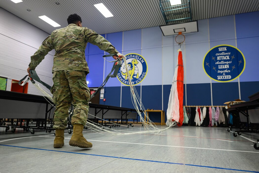 A U.S. Airman spreads out a parachute before a demonstration on basic physics to elementary school students at Spangdahlem Air Base, Germany.