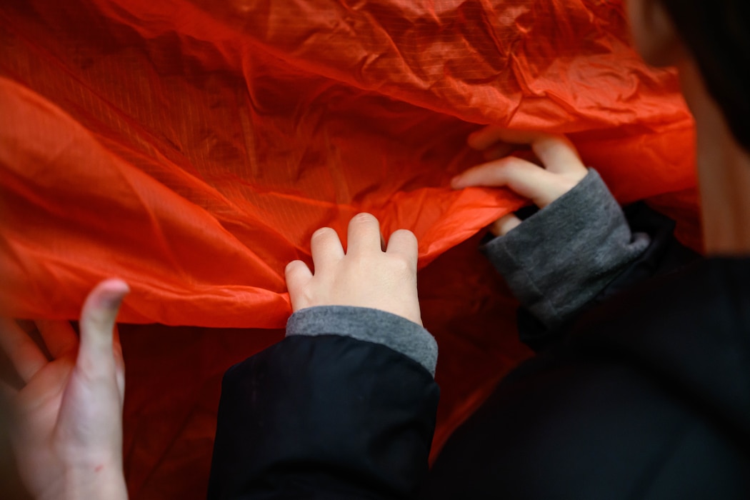 Third grade students feel the fabric of an Aces II parachute during a demonstration of motion and matter.
