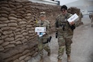 Two U.S. Army soldiers walk away from Logistics Support Area Danger’s dining facility with Operation Gratitude care packages in their hands in Erbil Air Base, Iraq, Dec. 14, 2025. Operation Gratitude supports U.S. service members with gratitude-filled care packages in effort to uplift spirits. (U.S. Army Photo by Pfc. Jordan Foster)