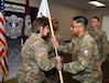 Capt. Justine Juan, right, commander of U.S. Army Medical Logistics Command’s Headquarters and Headquarters Detachment, passes the unit guidon to incoming detachment sergeant, Sgt. 1st Class Brandi Brown, during a change of responsibility ceremony Dec. 12, 2025, at Fort Detrick, Md. Also pictured are Sgt. 1st Class Aaron Taylor, background center, and outgoing detachment sergeant, Master Sgt. William Harbeson.