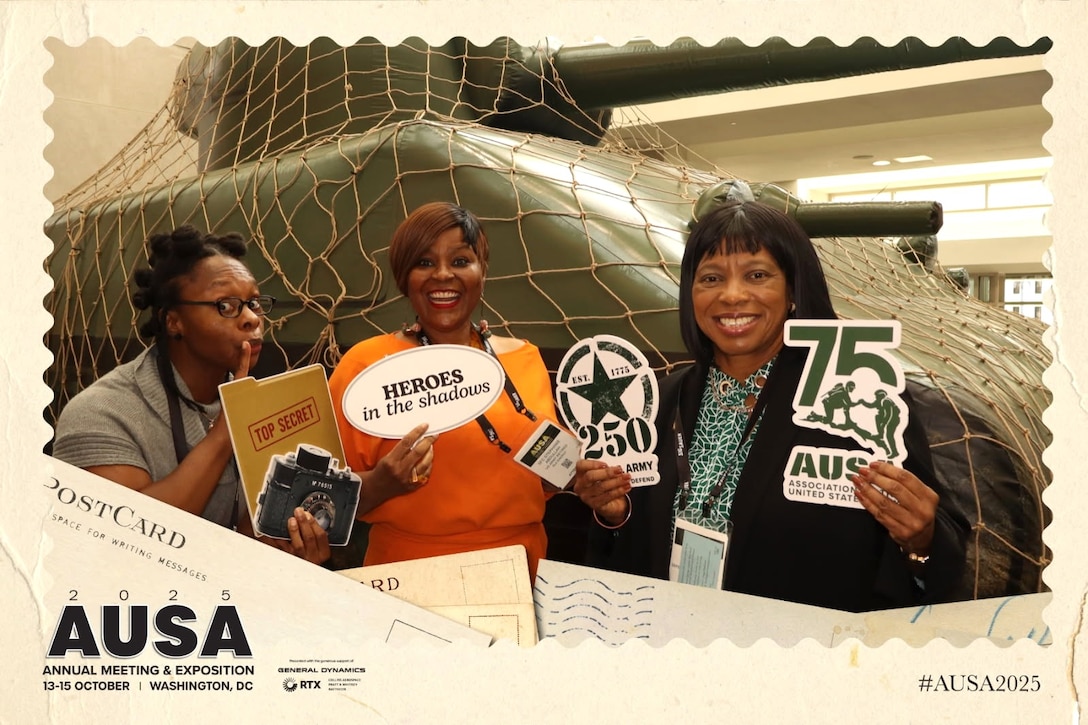 Three women pose in front of tank.