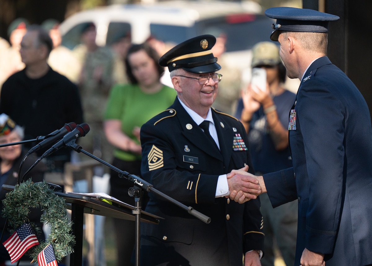 Ret. Army 1ST SGT, Veterans Tribute Tower Committee Chair, shakes hands with U.S. Air Force 96th Test Wing deputy commander during the Wreaths Across America Placement Ceremony.