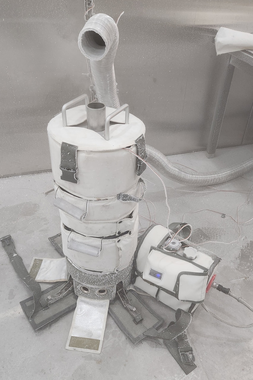 An insulated piece of metal equipment sits in a room filled with frost.