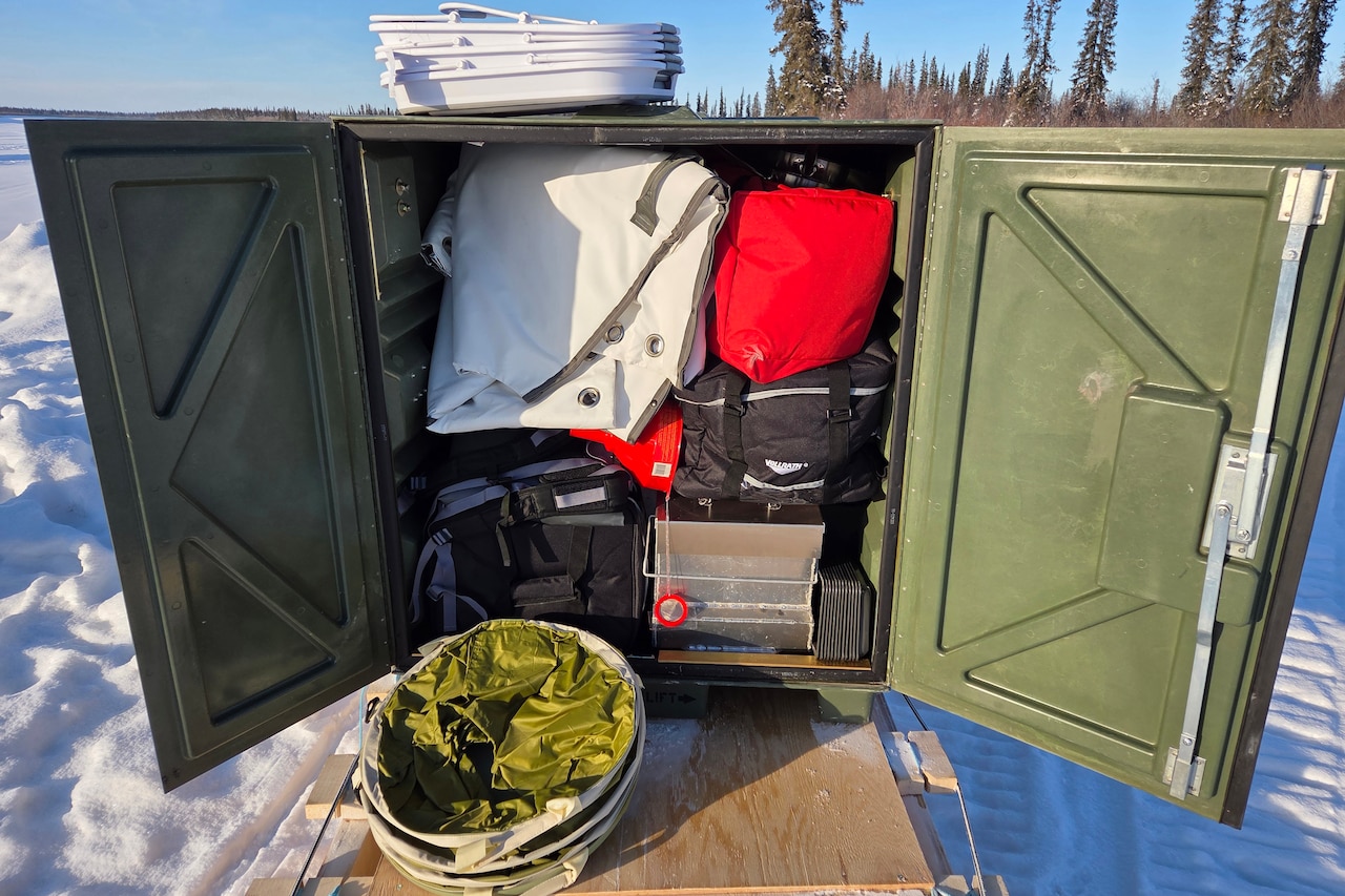 A large metal box is stuffed with durable bags, tarps and other items.