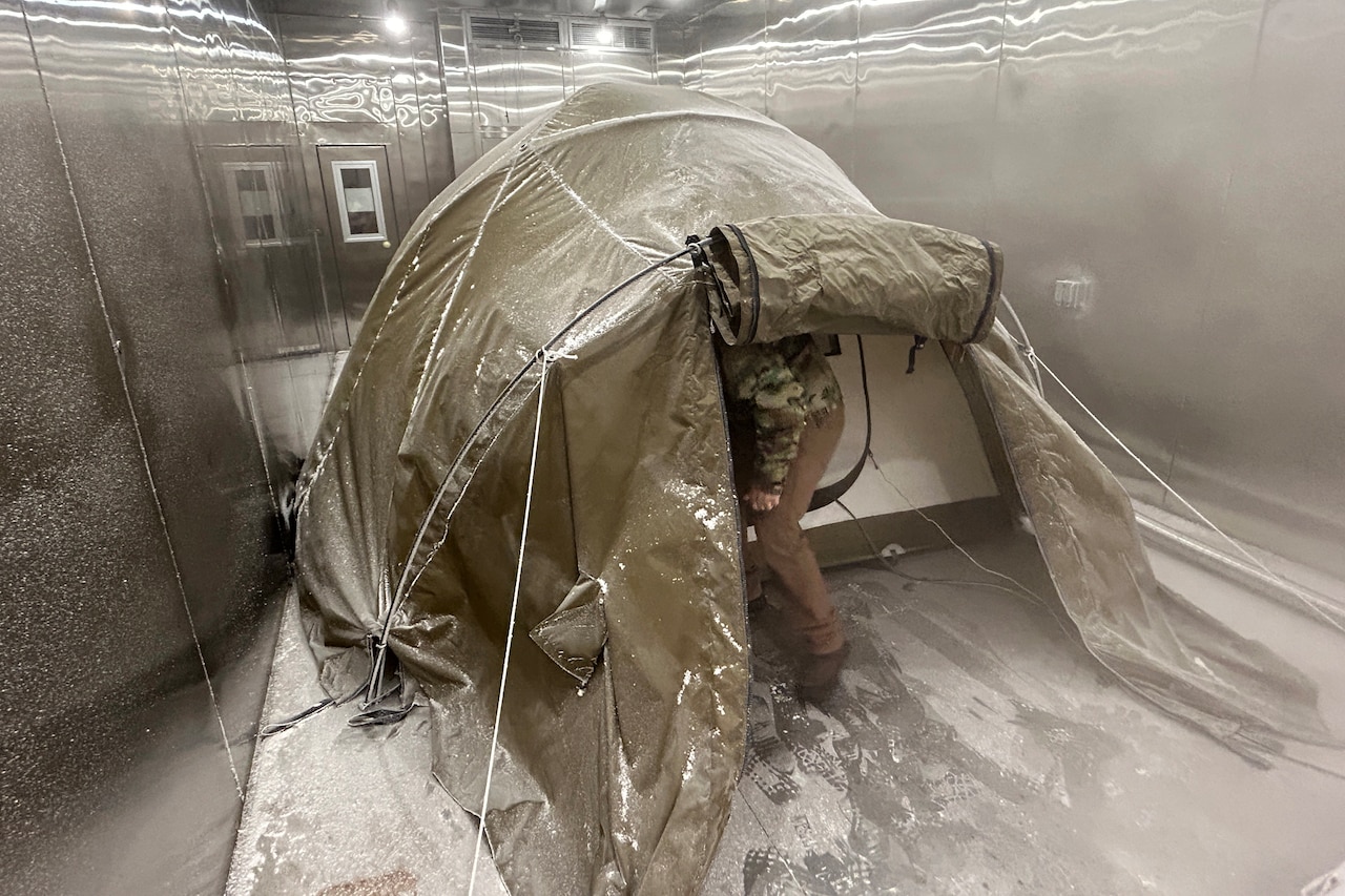 A tent sits inside a small steel room that has frost on its walls and ground.