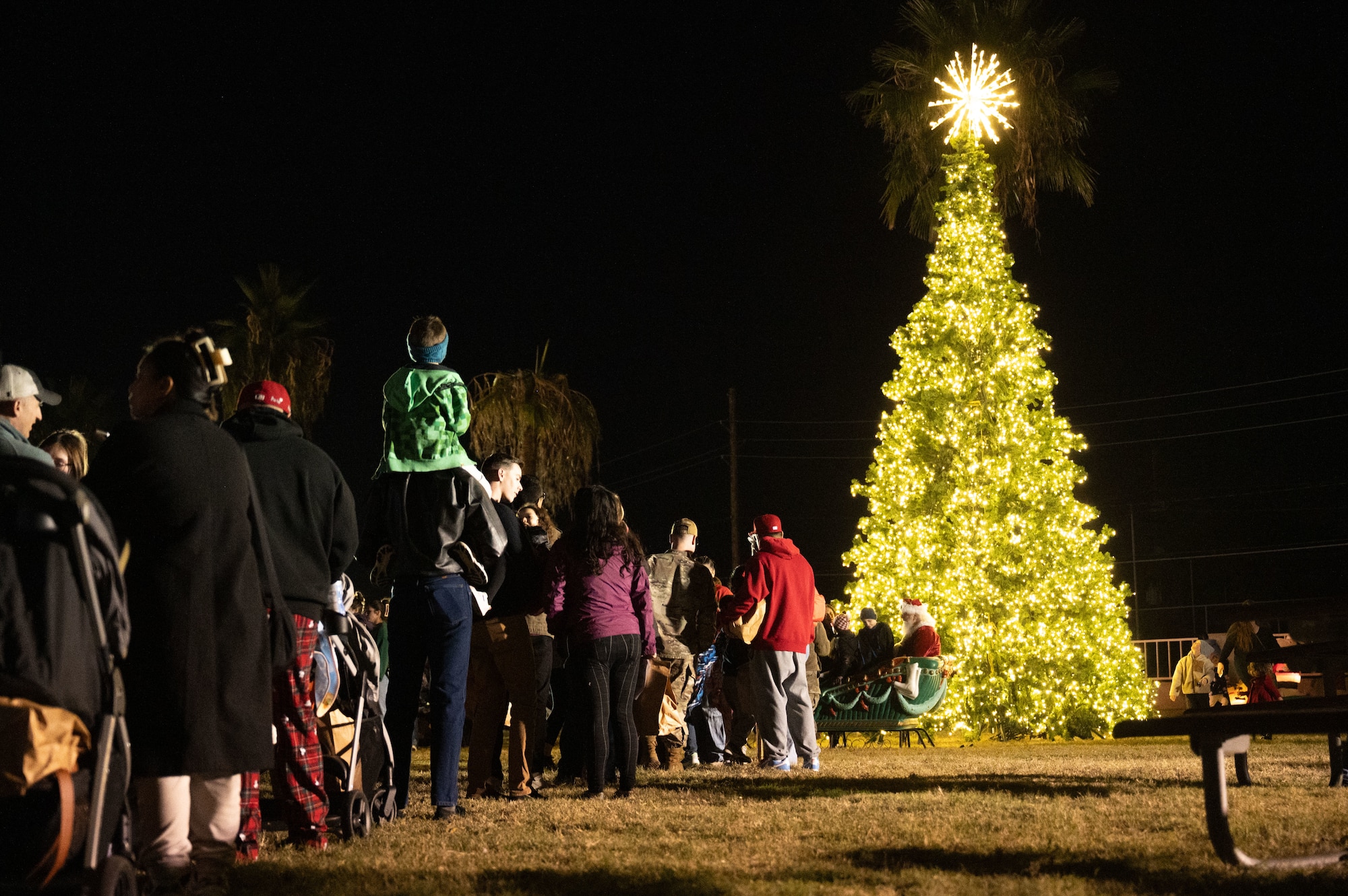 U.S. Air Force Airmen and civilians wait in line to meet Santa Claus during the 2025 Christmas Tree Lighting at Davis-Monthan Air Force Base, Arizona, Dec. 5, 2025. The event welcomed base families as part of the holiday season celebration. (U.S. Air Force photo by Airman 1st Class Jaden Kidd)