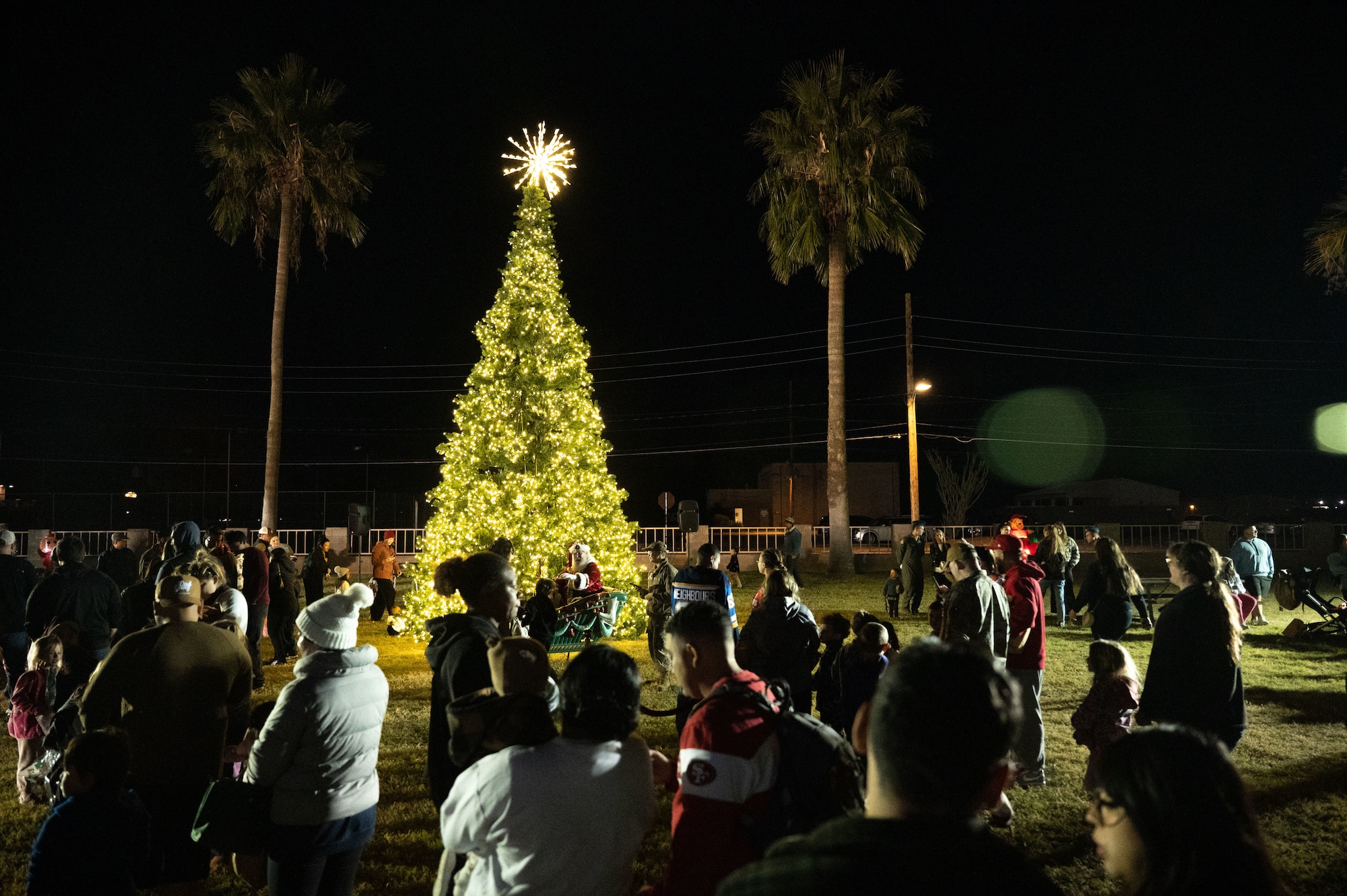 U.S. Air Force Airmen and members of the Desert Lightning Team line up to meet Santa Claus during the 2025 Christmas Tree Lighting at Davis-Monthan Air Force Base, Arizona, Dec. 5, 2025. The annual ceremony brought the DM community together to kick off the holiday season. (U.S. Air Force photo by Airman 1st Class Jaden Kidd)