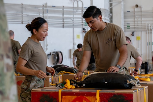 From left, U.S. Air Force Lt. Col. Kimberly McCoy-Singh, 374th Operational Medical Readiness Squadron, and Senior Airman Kain Flores, 374th Air Expeditionary Wing combat mobility flight combat mobility technician, secures a bundle.