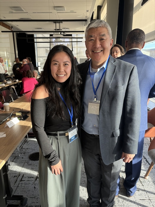 Woman and man in business casual dress smile together in a conference room