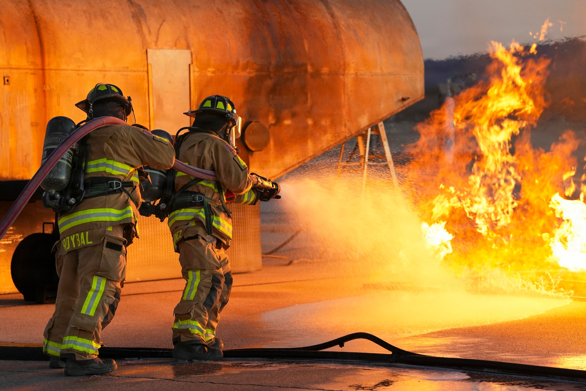 Two firefighters use a hose to extinguish a fire.