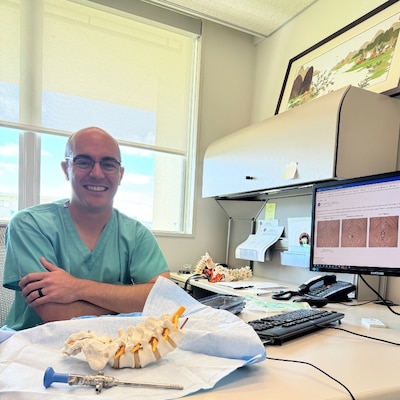 251217-N-TW242-1001Okinawa, Japan Dr. Lawless explains the surgical procedure in his office at USNHO (U.S. Navy photo by Public Affairs Officer Trey Savitz)