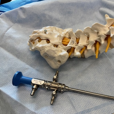 251217-N-TW242-1002 Okinawa, Japan Dr. Lawless explains the surgical procedure in his office with a spine visual aid at USNHO (U.S. Navy photo by Public Affairs Officer Trey Savitz)