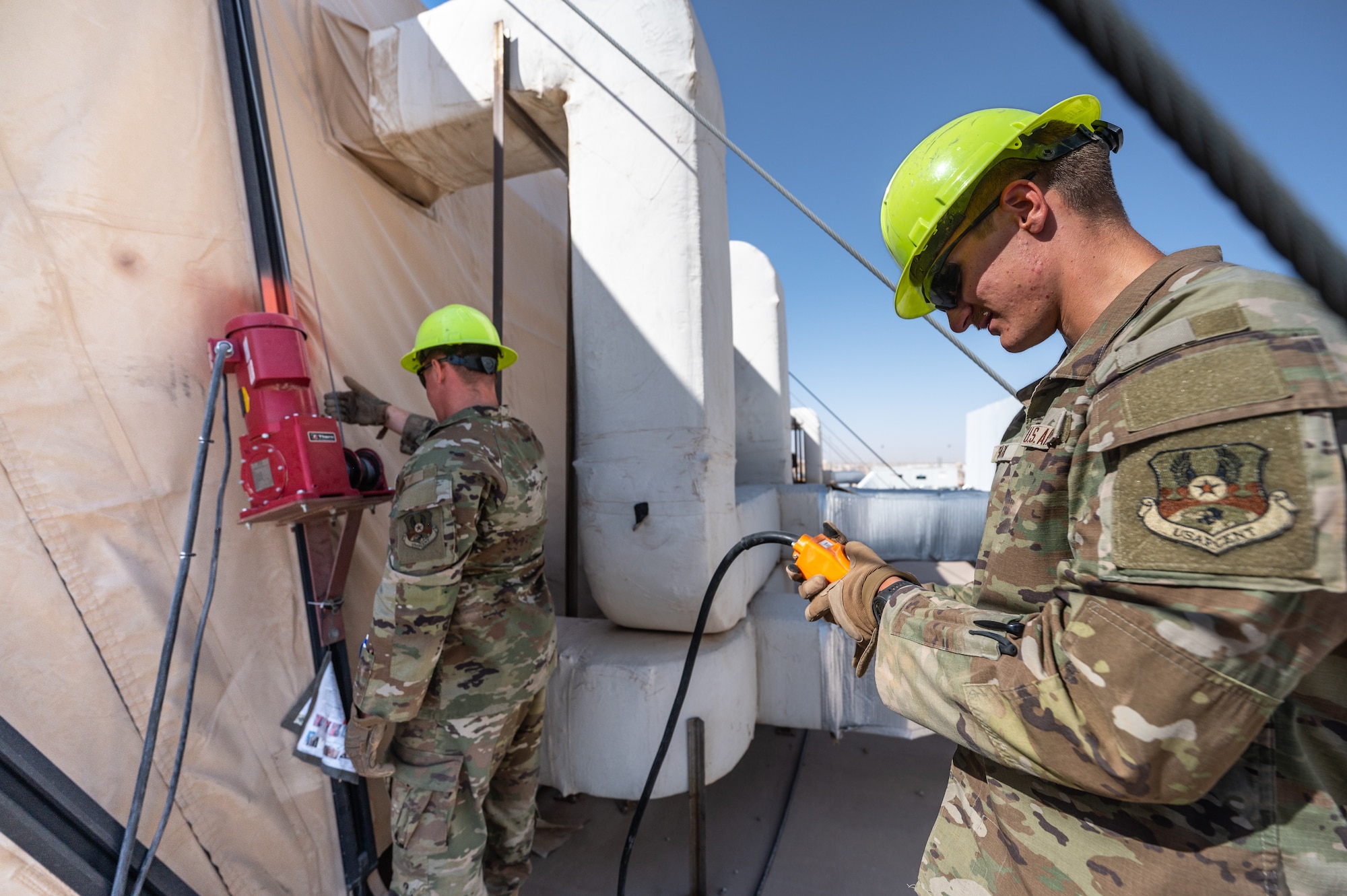 U.S. Air Force Senior Airman Austin Kirk, and Airman 1st Class Sean Stark, 378th Expeditionary Civil Engineer Squadron structural maintenance journeymen, inspect tension fabric systems on large area maintenance shelters