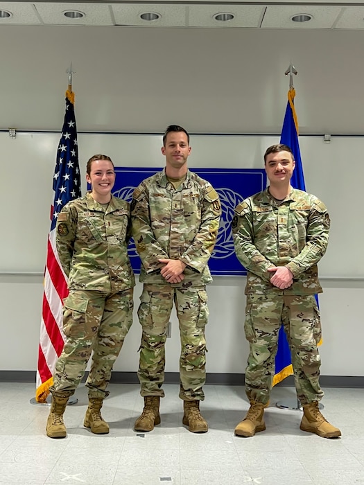 Three military members in uniform pose for a photo